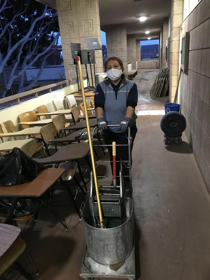 person pushing cart of cleaning supplies