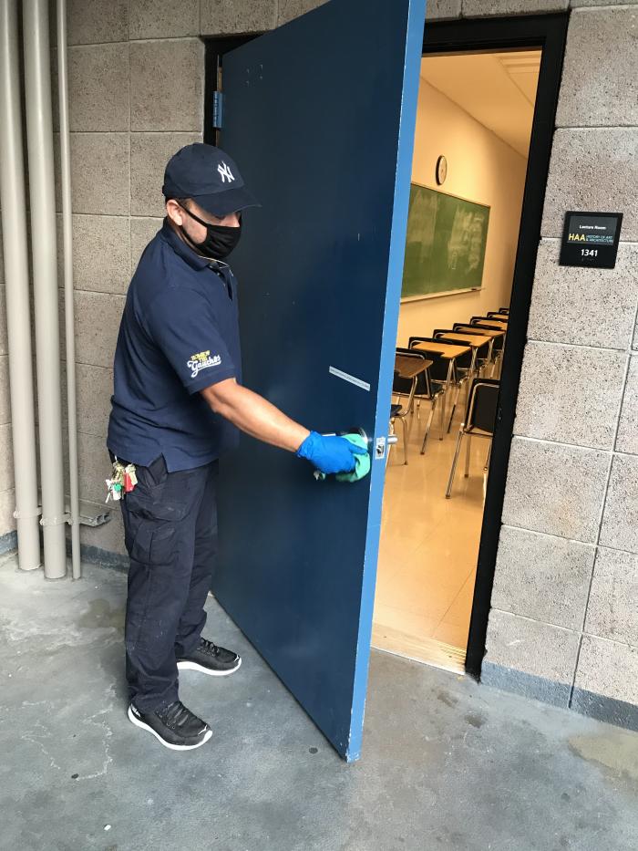 person cleaning doorknob