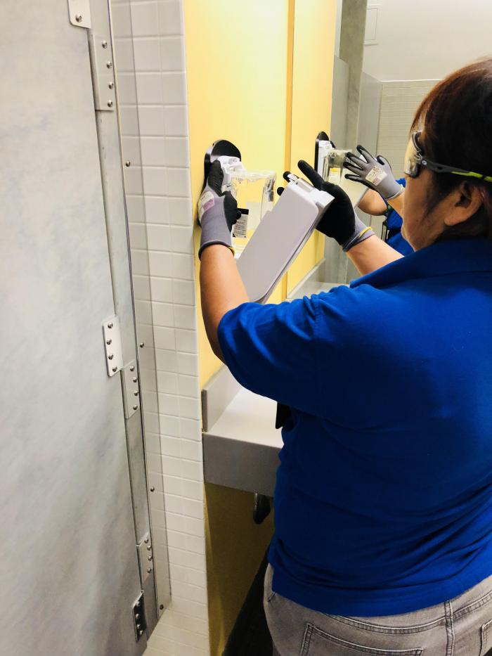 person installing soap dispenser in bathroom